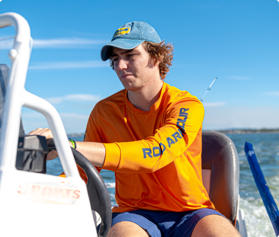 Rod Armour team member in an orange Rod Armour shirt driving a boat