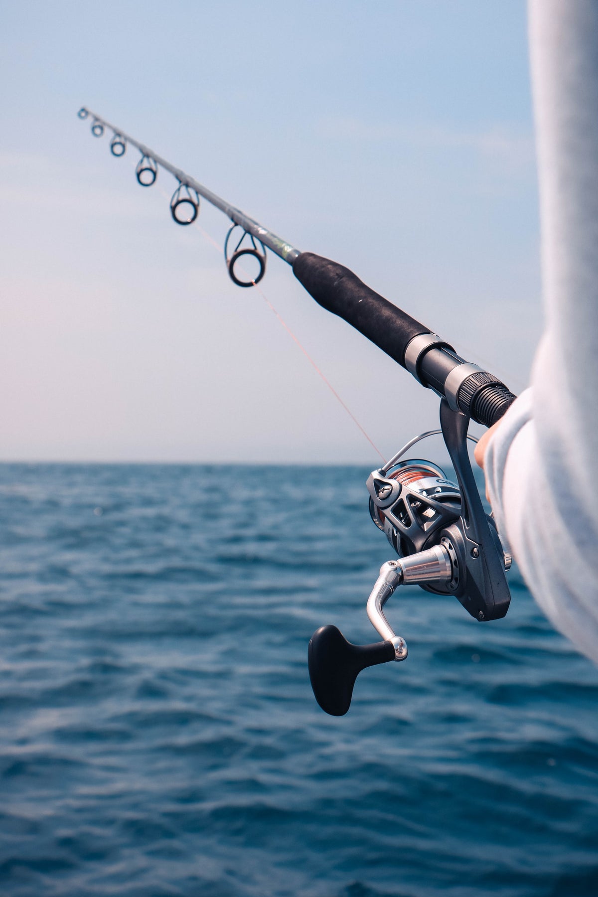 Man holding fishing rod over ocean