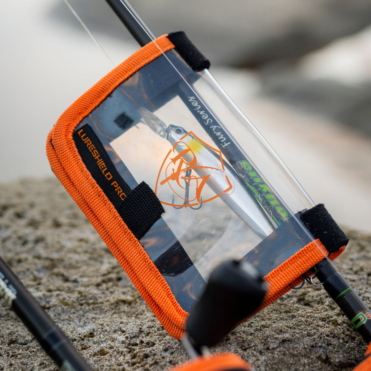 LureShield Pro XL strapped to a rod blank on the rocks, covering a rigged hard-body lure